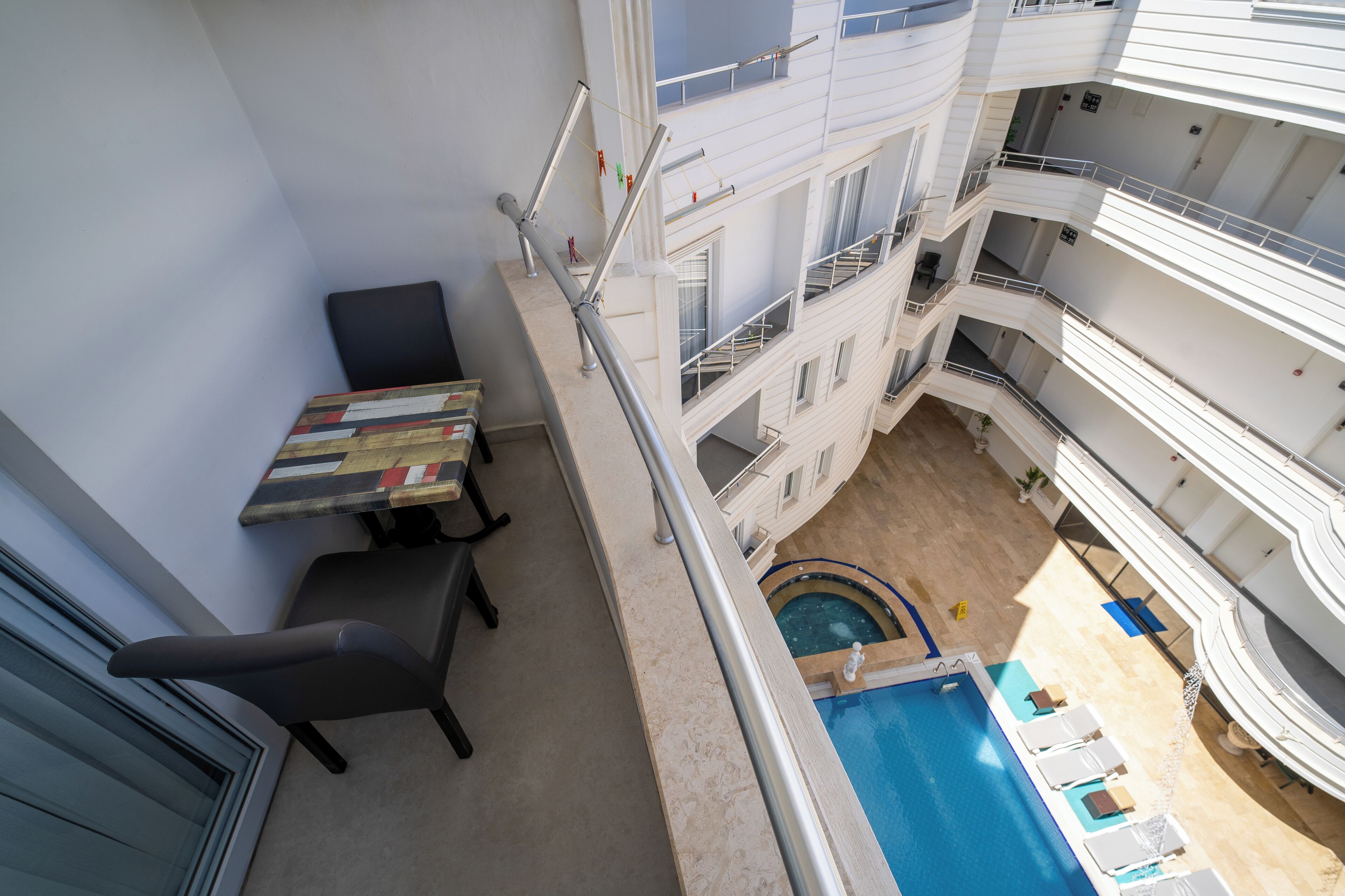 A multi-level hotel with a pool area, balconies, and a dining table with chairs.