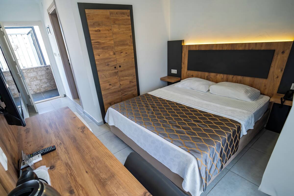 Een moderne hotelkamer met een houten bed, een bureau met een waterkoker, en uitzicht op buiten.