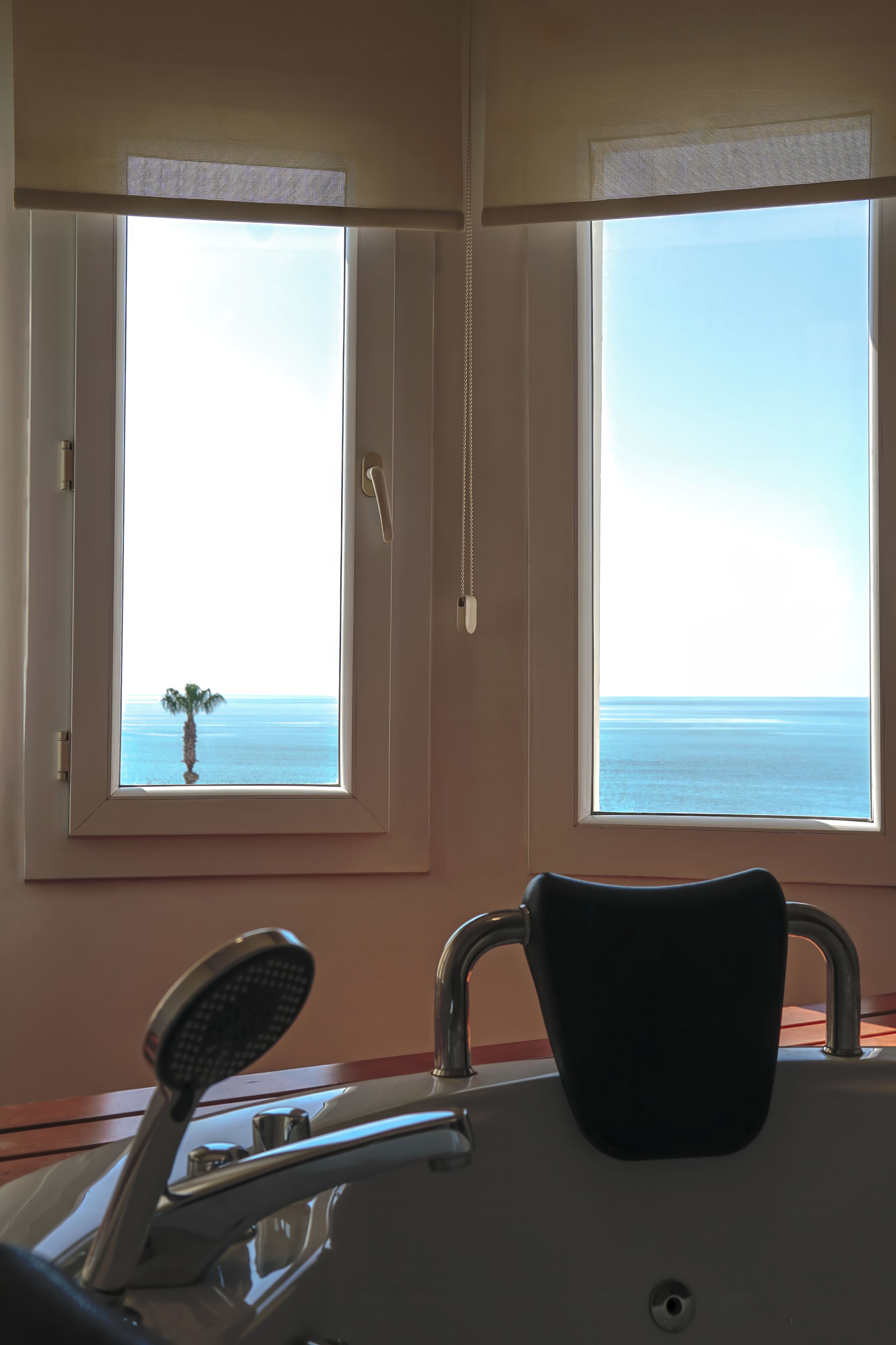Una habitación con vistas al mar a través de dos ventanas, una silla y una mesita.