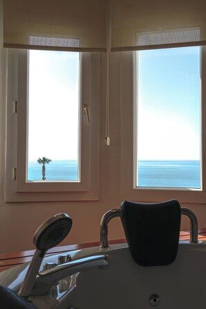 A room with a view of the sea through two windows, a chair, and a small table. - Club Efes Otel (Silifke)