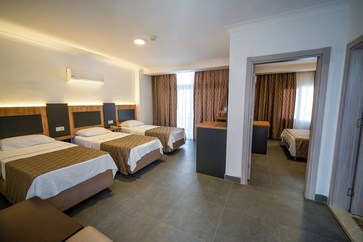 Hotelkamer met drie bedden, een bureau en een badkamer die door een open deur zichtbaar is.