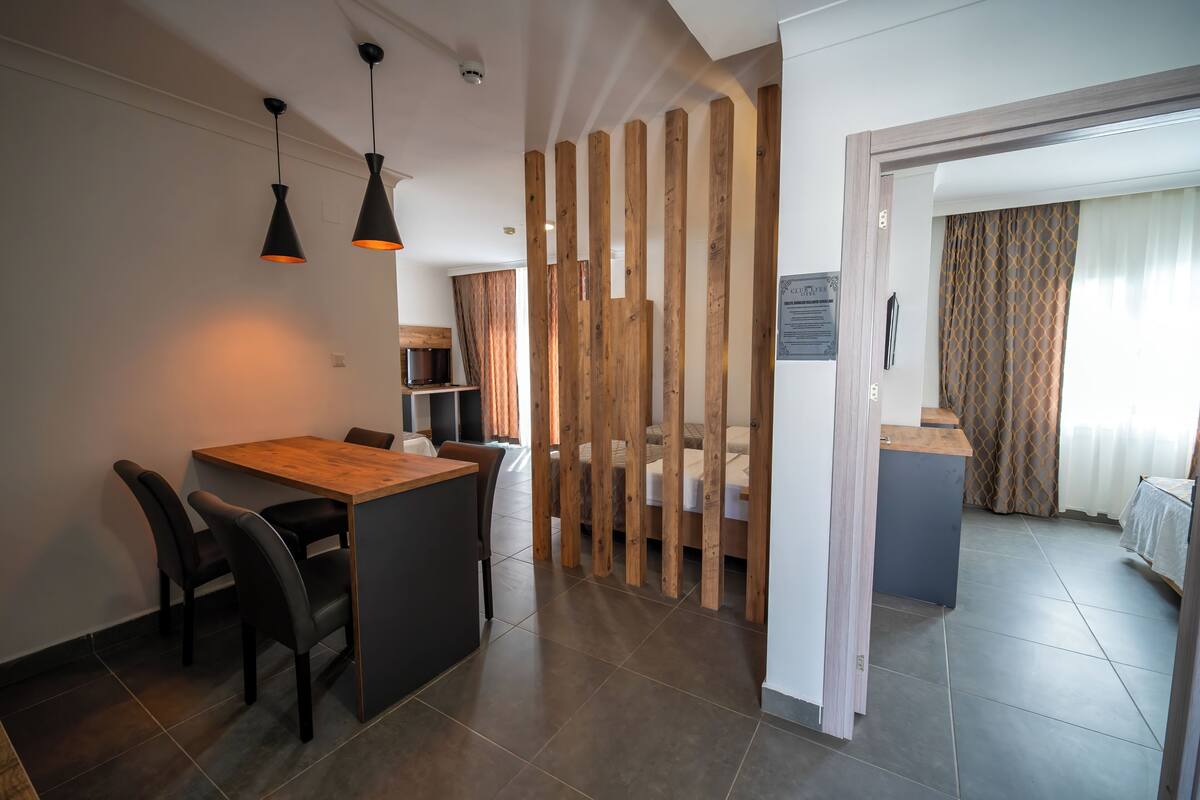 Een moderne keuken met een houten eettafel, zwarte stoelen en hanglampen.
