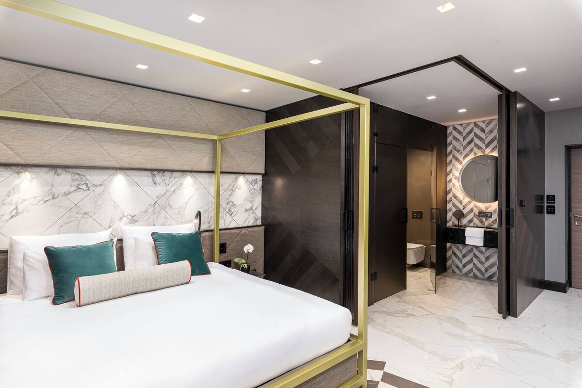 A modern hotel room with a bed, a bathroom, and a walk-in closet.