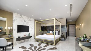 Un dormitorio moderno con una cama grande, televisión, escritorio y zona de baño.