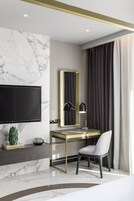 Una habitación de hotel moderna con una pared de mármol, un televisor de pantalla plana, un escritorio con lámpara y una silla.