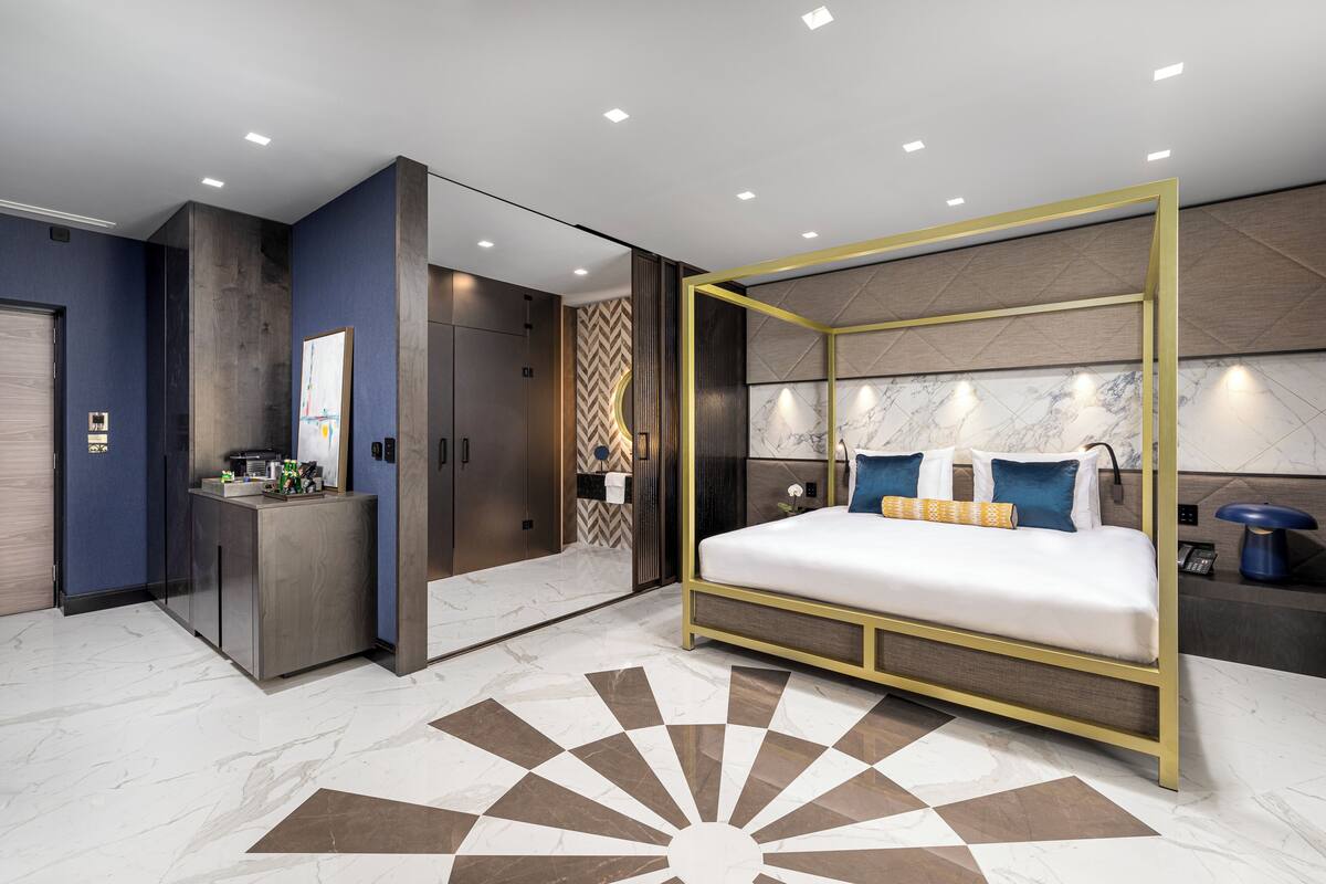 A modern bedroom with a large bed, a vanity, and a walk-in closet.