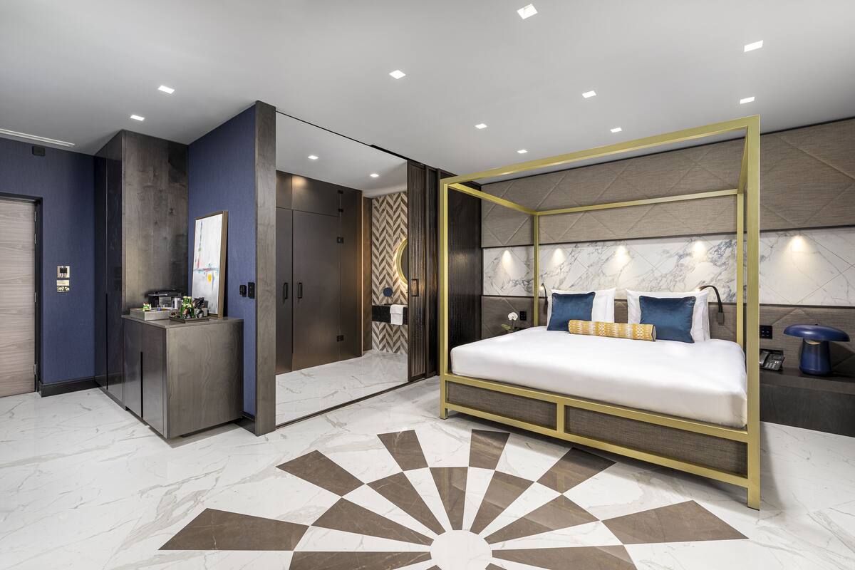 A modern bedroom with a large bed, a vanity, and a walk-in closet.