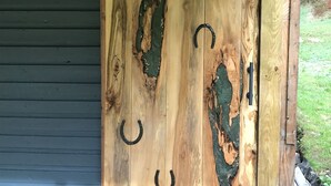 A wooden door with horse-shaped cutouts and metal hinges.