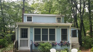 A two-story house with a porch, numbered 53, surrounded by lush greenery.