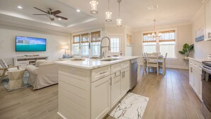 A spacious kitchen with a large island, white cabinetry, and pendant lighting. - Serenity Tides PCB- Golf Cart, Games, MiniGolf & Dogs OK – 3 Blocks to Beach (Panama City Beach)