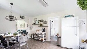 A modern kitchen with a white refrigerator, a dining table with chairs, and a hanging light fixture. - Cedar Creek Cottage-Idyllic Setting & Dog Friendly (Cedar)