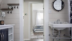 A bathroom with a white sink, a round mirror, and a shower area. - Cedar Creek Cottage-Idyllic Setting & Dog Friendly (Cedar)