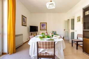 A dining area with a round table set for four, surrounded by plaid chairs. A television is mounted on the wall, and there are framed pictures on the walls. - 1940 Appartamento Fiorella by Barbarhouse (Gallipoli)
