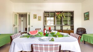 A dining area with a round table set for four, surrounded by chairs. A large glass cabinet with books and decorative items is visible in the background. - 1940 Appartamento Fiorella by Barbarhouse (Gallipoli)