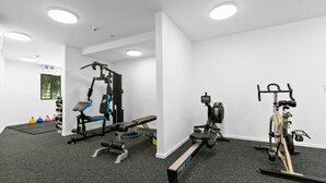Une salle de sport équipée d’appareils d’exercice, d’un banc et d’un vélo fixé au mur.