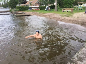 Una persona en el agua, con una casa y un columpio al fondo.