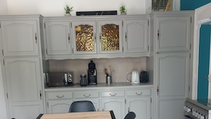 A modern kitchen with grey cabinets, a wooden dining table, black chairs, and a patterned rug.