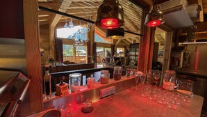 A bar area with a wooden counter, various glassware, and a red-lit ceiling.