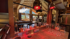 A bar area with a wooden counter, glassware, and a red-lit ambiance.