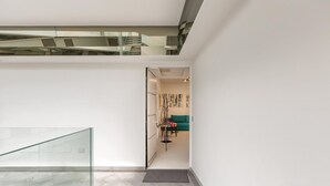 Um interior moderno com escadaria de vidro, sala de estar com sofá e obras de arte, e design minimalista.