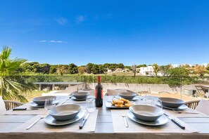 A dining table set for four with a bottle of wine, plates, bowls, and cutlery. - 1937 Bella Vita Appartamento Simone (Gallipoli)