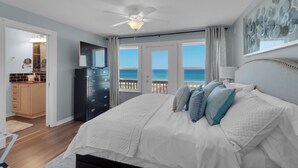 Une chambre avec un lit, un ventilateur de plafond et une vue sur l’océan.