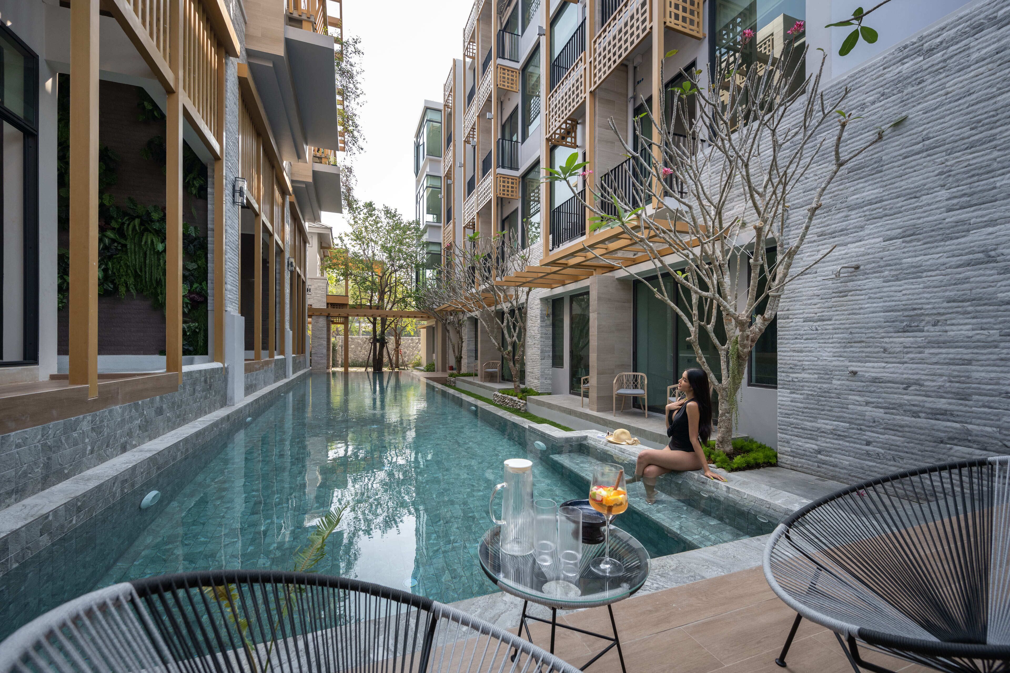 Un espace piscine moderne avec une piscine à eau claire, des chaises longues et une table avec des boissons.