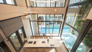 Uma área de refeições moderna com uma mesa grande, cadeiras e vista para uma piscina.