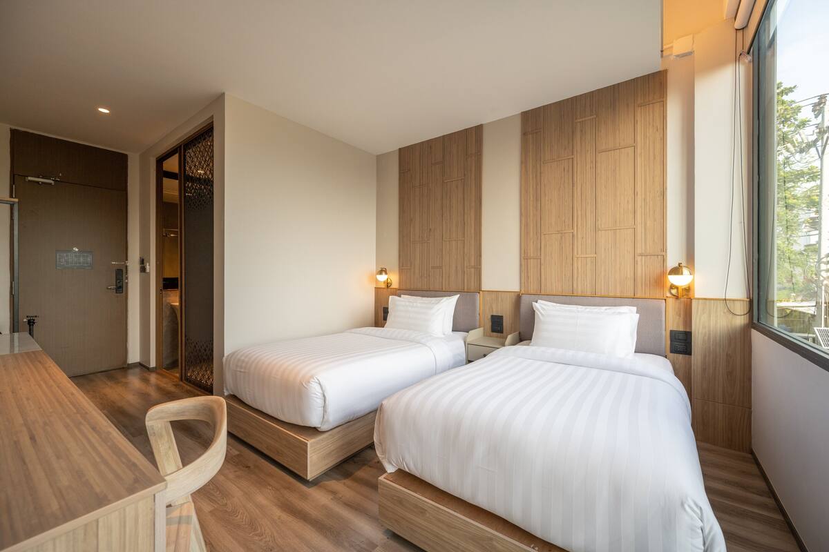 Ett hotellrum med två sängar, ett skrivbord i trä och utsikt över omgivningarna.