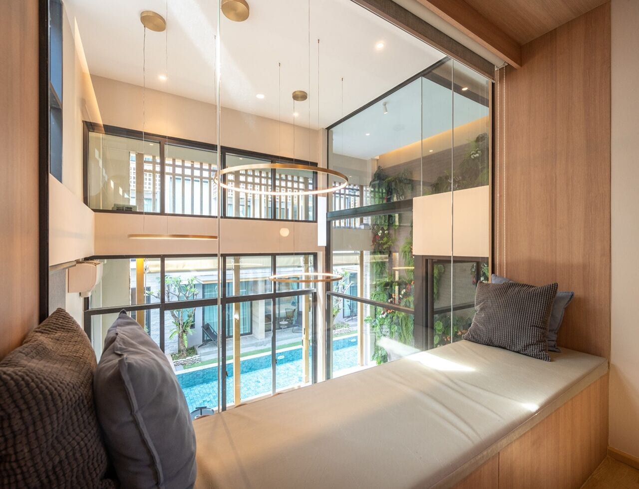 A modern room with a large window seat overlooking a pool and outdoor area.