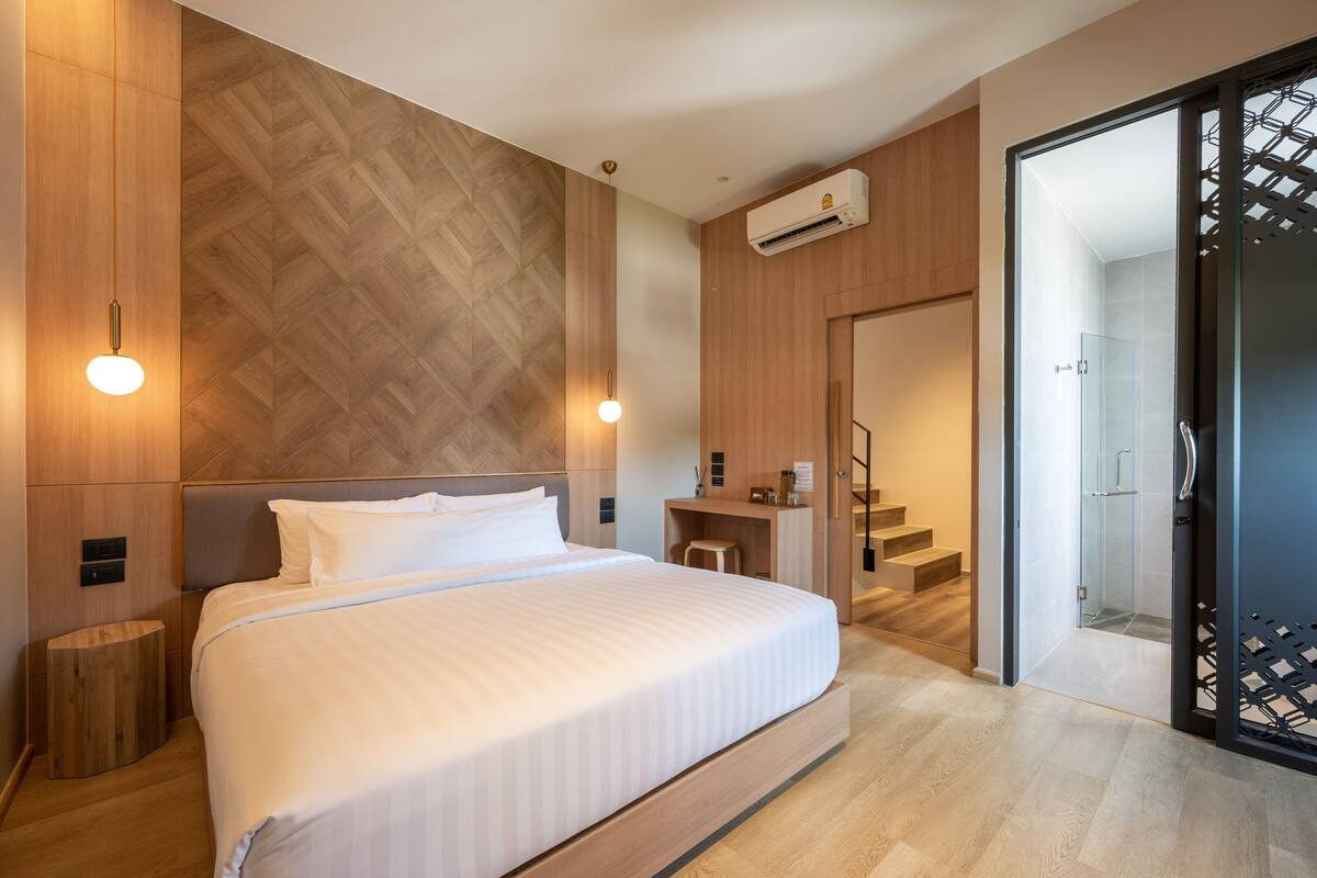 Ett modernt hotellrum med en stor säng, ett skrivbord och en duschhörna.