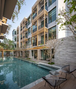 Residents can enjoy a relaxing outdoor space with a pool, lounge chairs, and a table.