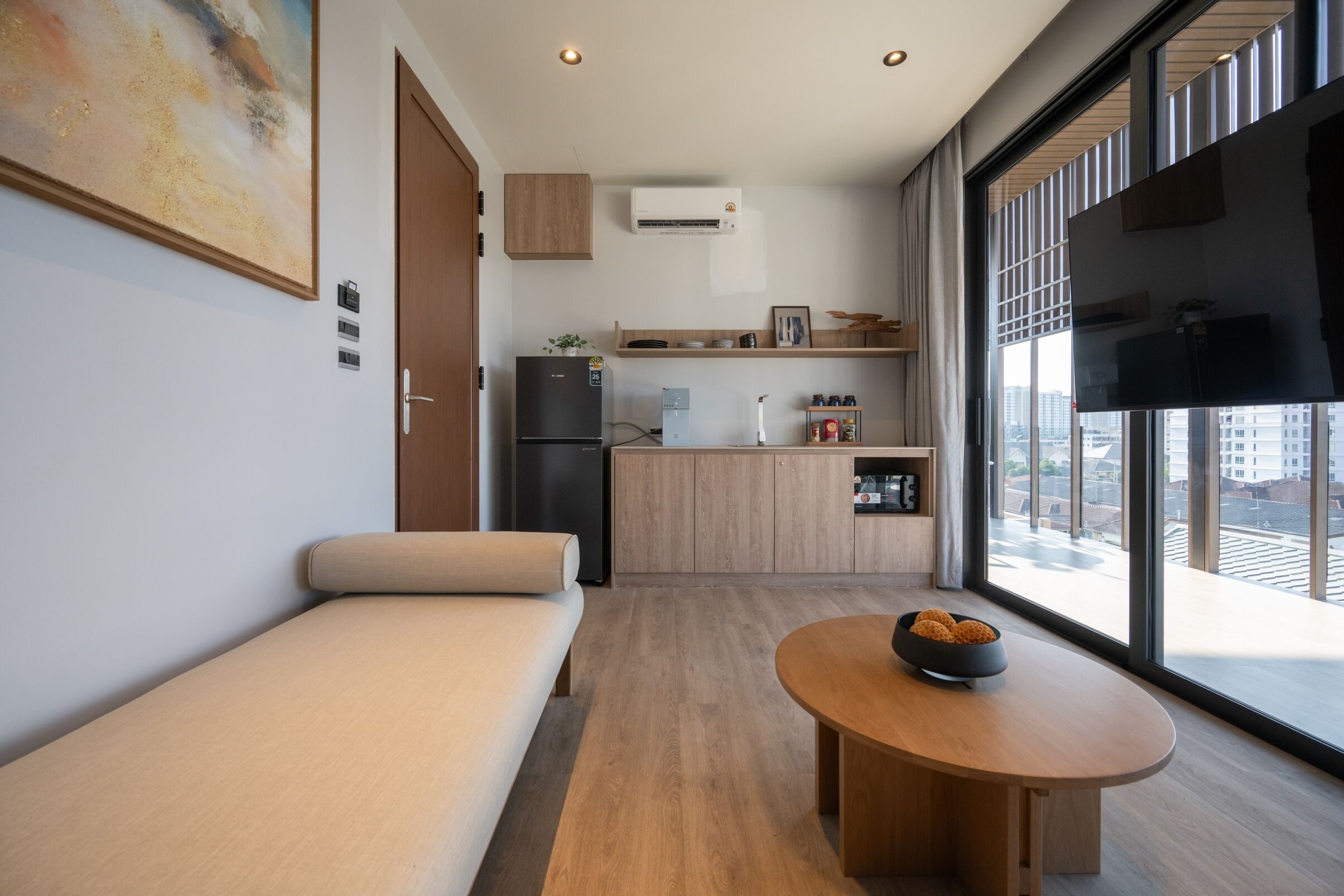Eine moderne Wohnung mit Küchenzeile, einer Couch, einem Esstisch und einem großen Fenster mit Blick auf die Stadt.