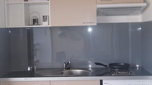 A compact kitchen with a stove, sink, and washing machine. - Ocean view, 2-minute walk to the beach (Le Moule)