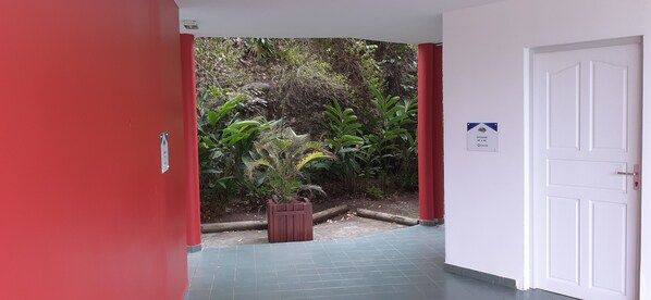 A hallway with a red wall, a white door, and a sign indicating 'STUDIOS 85 & 88'. - Ocean view, 2-minute walk to the beach (Le Moule)
