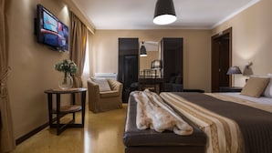 A hotel room with a bed, a sofa, a small table with a vase, a television on the wall, and a mirror. - APARTMENT San Moisè Terrace! 90mt St.MARK\'S square (Venezia)