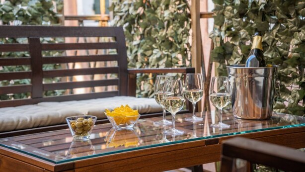 A glass table with a bottle of champagne, several wine glasses, and a bowl of snacks. - APARTMENT San Moisè Terrace! 90mt St.MARK\'S square (Venezia)