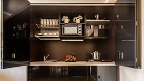 A compact kitchen with a built-in microwave, a stove, and a sink. There are potted plants on the countertop and a small refrigerator to the right. - APARTMENT San Moisè Terrace! 90mt St.MARK\'S square (Venezia)
