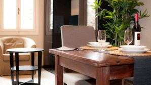 A dining area with a wooden table set for two, a small round table, a sofa, and a potted plant. - APARTMENT San Moisè Terrace! 90mt St.MARK\'S square (Venezia)