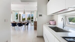 Une cuisine moderne avec une grande fenêtre, un grille-pain rose et un coin repas comprenant des chaises et une table.