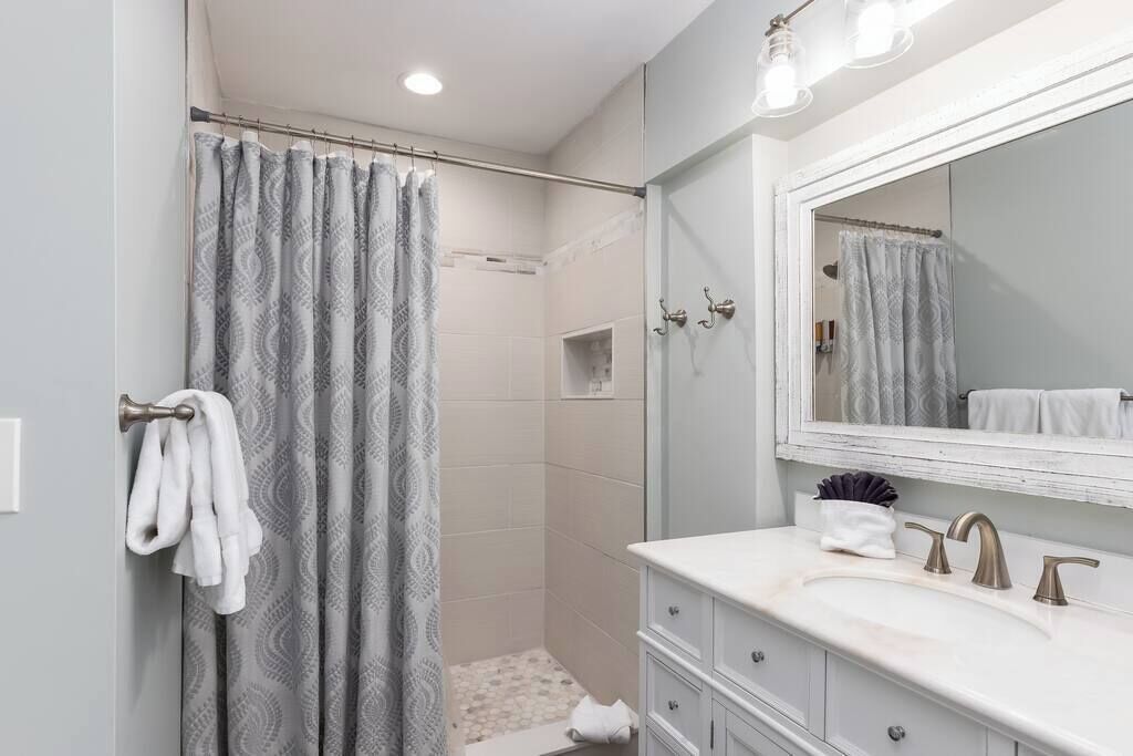 A bathroom with a shower, a sink with a mirror, and a towel rack.