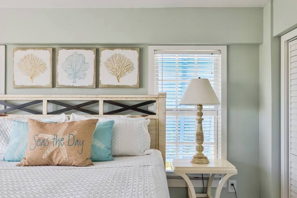 Un dormitorio con cama, mesita de noche, lámpara y decoración en la pared.