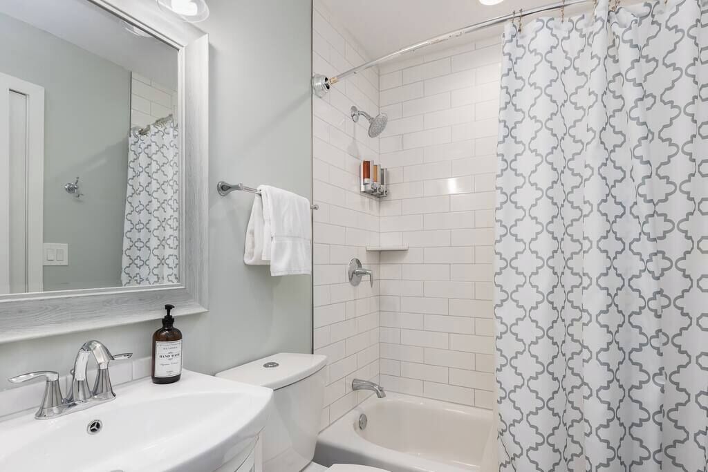 A bathroom with a white sink, a toilet, a bathtub, and a shower curtain with a geometric pattern.
