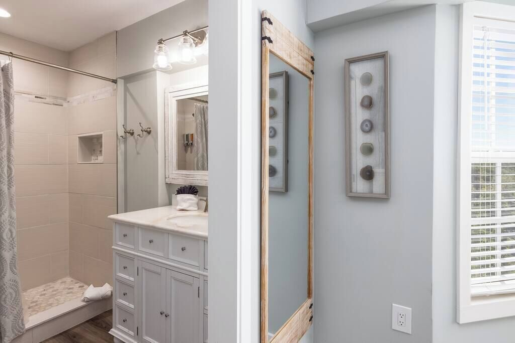 A bathroom with a shower, vanity, and a large mirror.