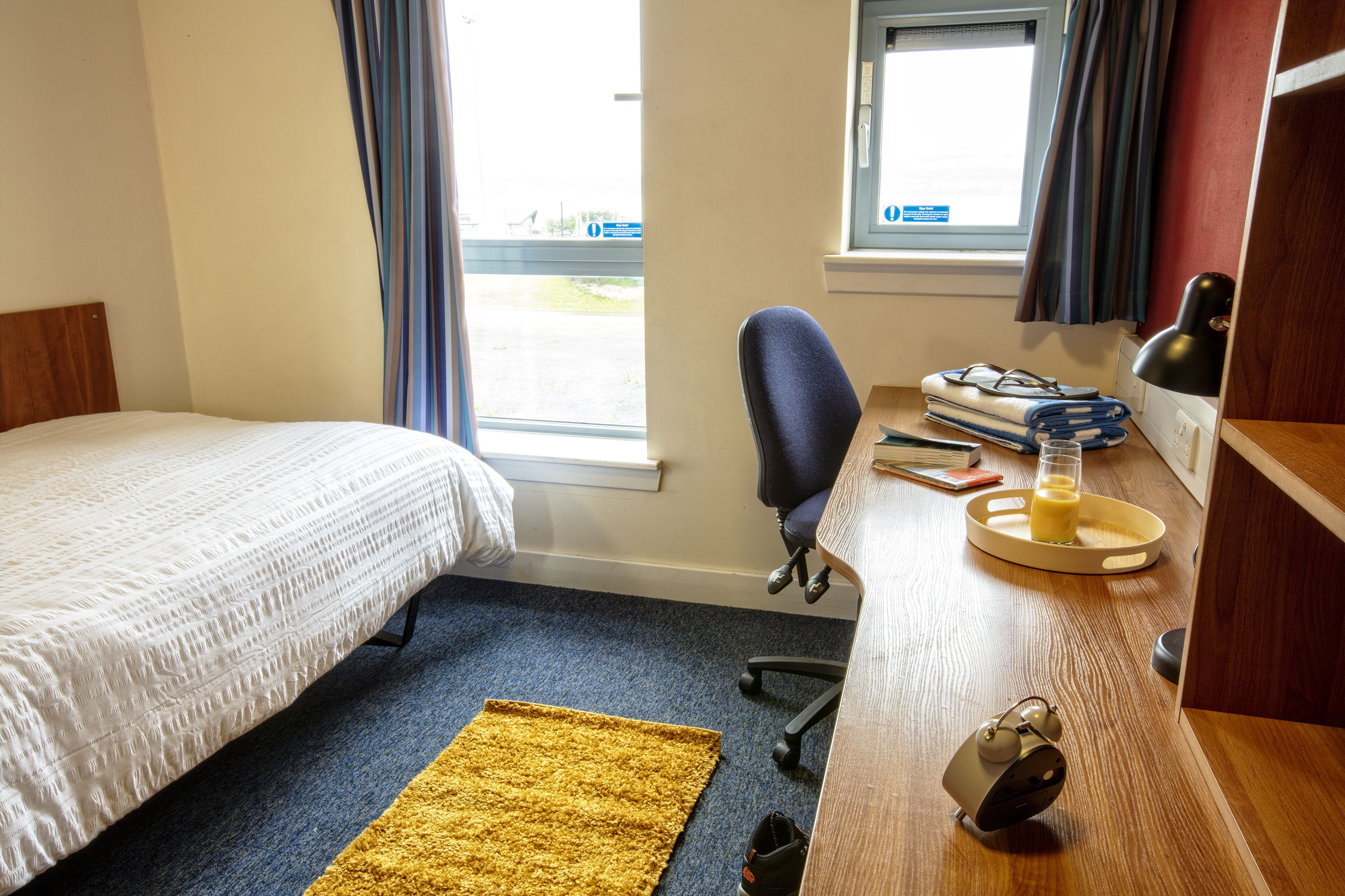 A hotel room with a bed, a desk with a chair, a window, and a view of the outside.