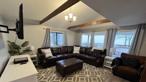 A living room with a sectional sofa, a coffee table, and a TV mounted on the wall.