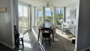 A room with a dining table, chairs, a ceiling fan, and a desk with a computer.