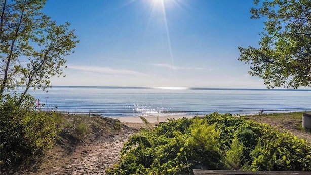 A beach view with a clear sky and sunlight reflecting on the water.