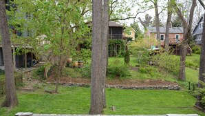 A residential backyard with a stone border, trees, and a small garden area. - Elegant Retreat in Montford Victorian! (Asheville)