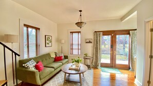 A living room with a green sofa, a coffee table, and a staircase. - Elegant Retreat in Montford Victorian! (Asheville)